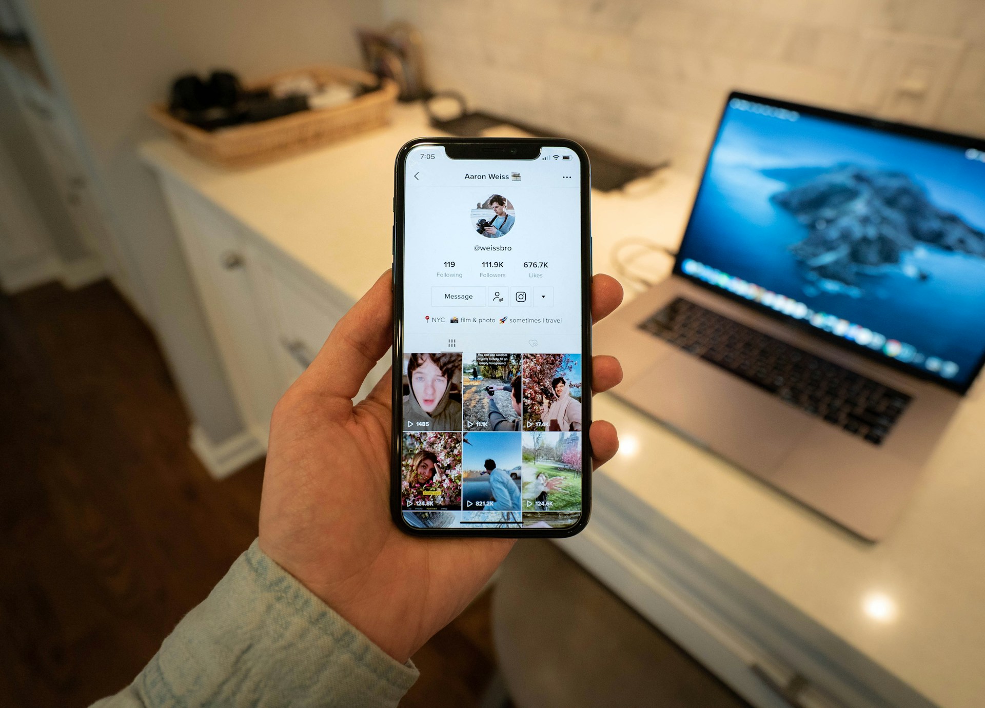 A person holding a smartphone showing a TikTok profile.